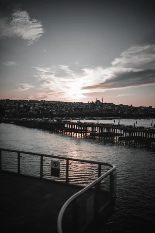 the sun is setting over a body of water, a black and white photo, pexels contest winner, fallout style istanbul, wood pier and houses, today\'s featured photograph 4k, scenic view of river