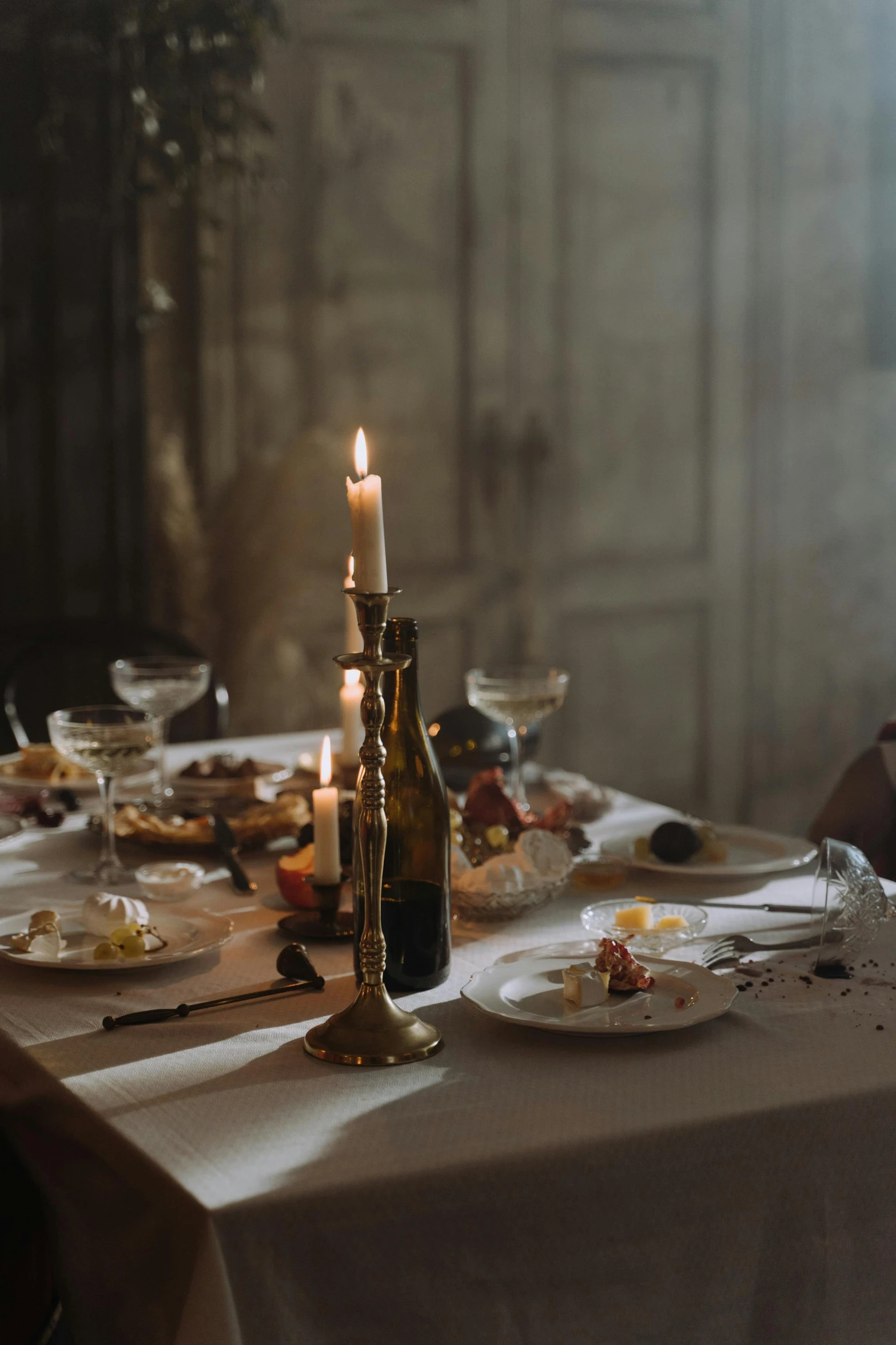 a candle sitting on top of a table next to plates of food, by Elsa Bleda, renaissance, wine, mess, castle setting, gold hour light