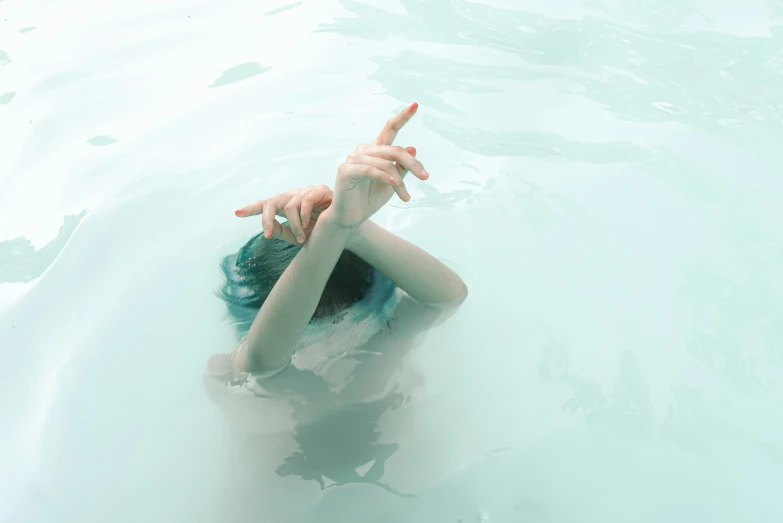a person in a body of water with their hands in the air, an album cover, inspired by Elsa Bleda, pexels contest winner, conceptual art, pale blue skin, with index finger, green oozing pool pit, high angle shot