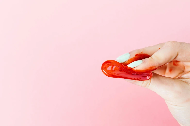 a close up of a person holding a red object, by Julia Pishtar, pastel cute slime, high quality product photography, sauce, artery