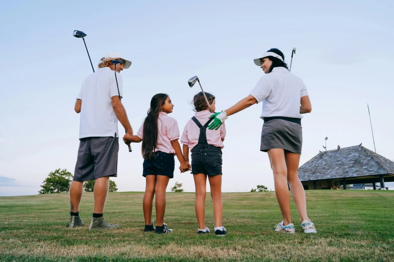 a group of people standing on top of a grass covered field, wearing golf shorts, kids, profile image, alana fletcher
