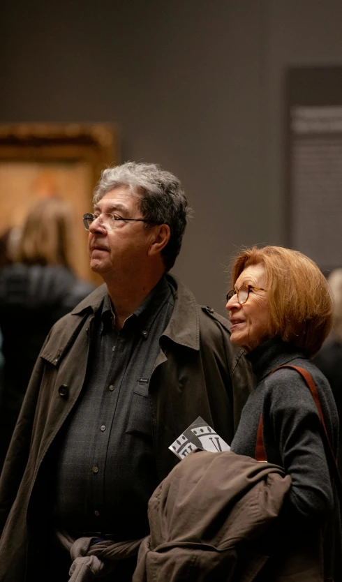 a couple of people standing next to each other, a photo, by Leo Michelson, national gallery, audience, promo image, parents watching