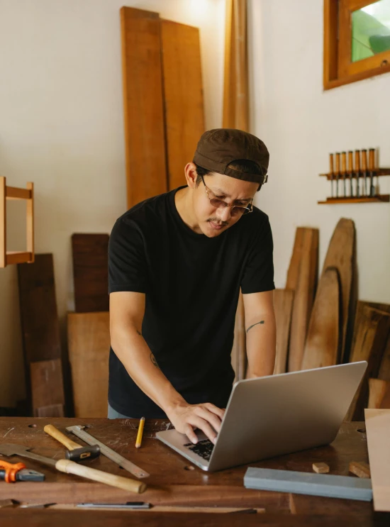 a man working on a laptop in a workshop, by Everett Warner, trending on pexels, arbeitsrat für kunst, asian male, made of woods, avatar image, full body image