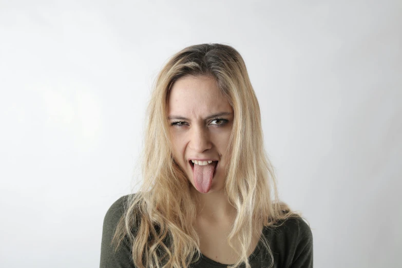 a woman with long blonde hair sticking out her tongue, a picture, trending on pexels, default pose neutral expression, very ugly face, language, mid 2 0's female