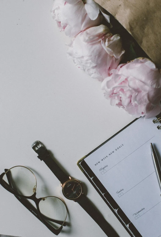 a notepad sitting on top of a table next to a bunch of flowers, objects, multiple stories, day time, item