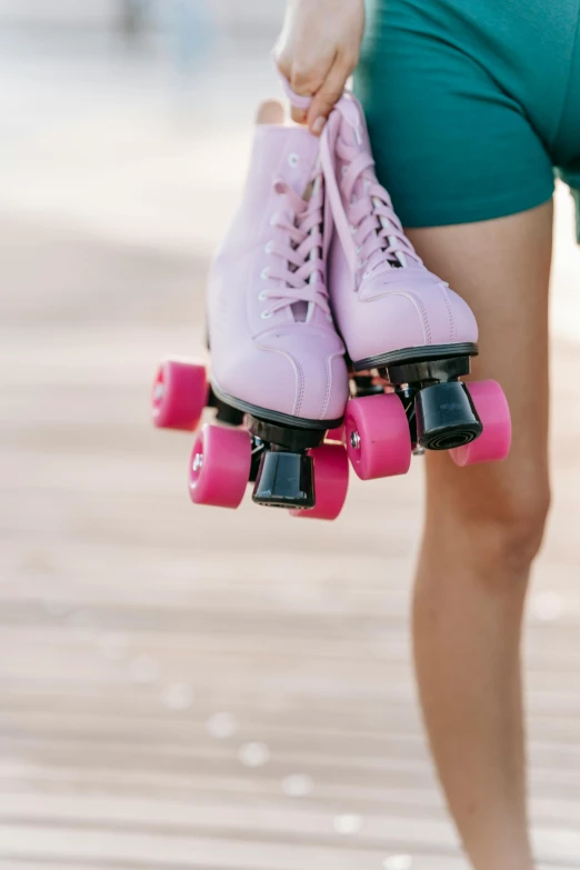a woman holding a pair of pink roller skates, standing on a skateboard, upon a peak in darien, upclose, trending on