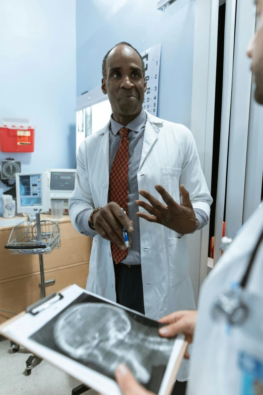 a couple of men standing next to each other in a room, a photo, by Dan Luvisi, male physician, talking, chad, f / 2 0