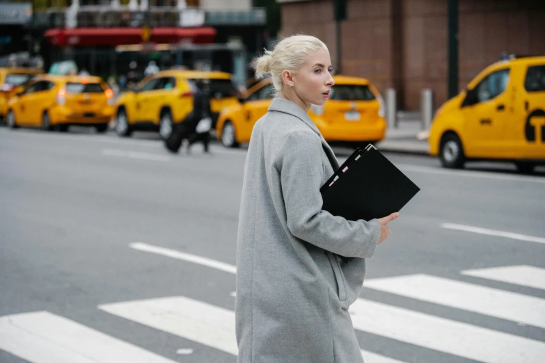 a woman in a gray coat is walking across the street, by Adam Rex, pexels contest winner, holding notebook, anya taylor joy, people at work, girl with short white hair