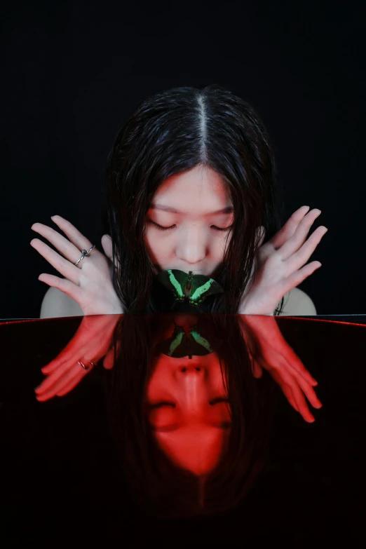 a woman holding a rose in front of her face, an album cover, inspired by Ren Hang, sitting in a reflective pool, fangs and slime, in a black room, red and green