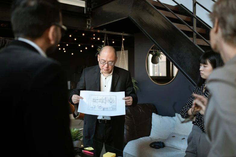 a group of people standing around a living room, norman foster, storyboarding, wearing a suit and glasses, wedding