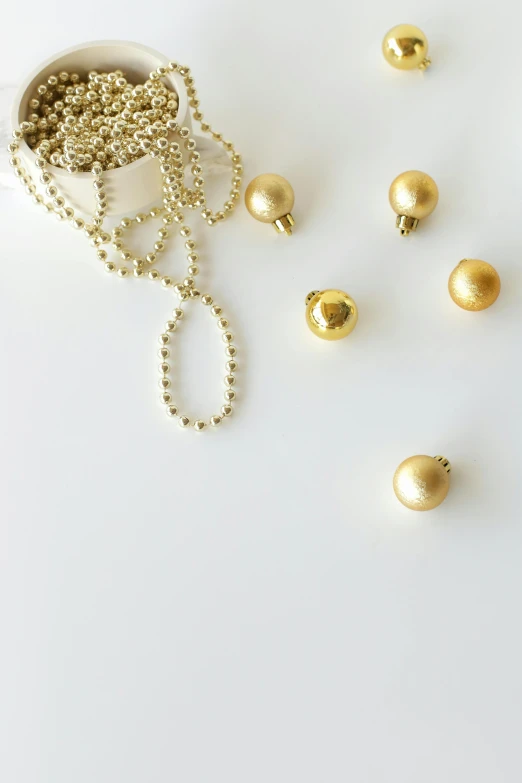 a white bowl filled with lots of gold beads, by Nina Hamnett, minimalism, pendants, holiday, knobs, ball