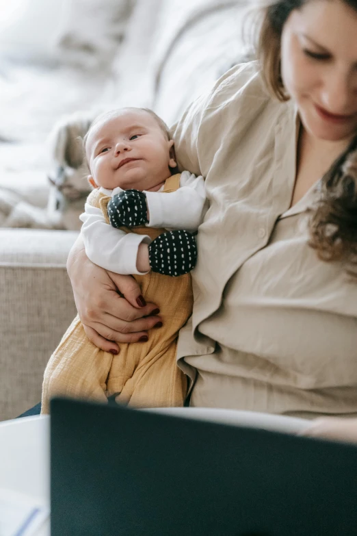 a woman sitting on a couch holding a baby, pexels, closeup of arms, worksafe. instagram photo, lightly dressed, gen z