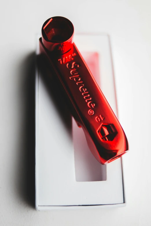 a red lighter sitting on top of a white box, inspired by Eugène Brands, unsplash, superflat, engraved blade, supreme, embedded in clear epoxy, hypersaturated