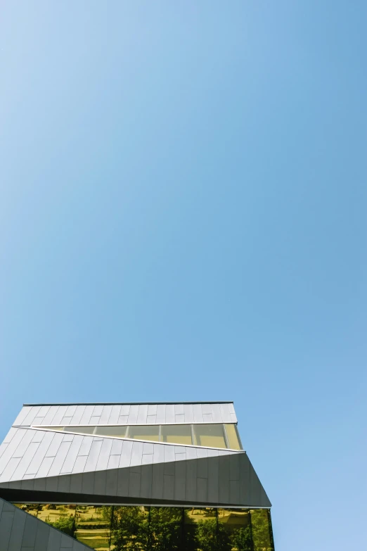 a tall building sitting on top of a lush green hillside, a picture, by Peter Churcher, postminimalism, cloudless blue sky, rinko kawauchi, museum quality photo, low angle photograph