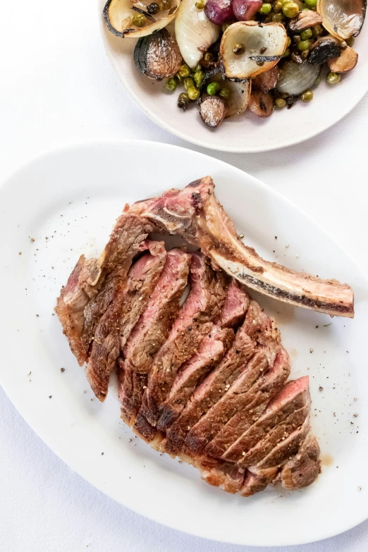 a steak sitting on top of a white plate next to a bowl of vegetables, long horns, full upper body, long, side profile centered