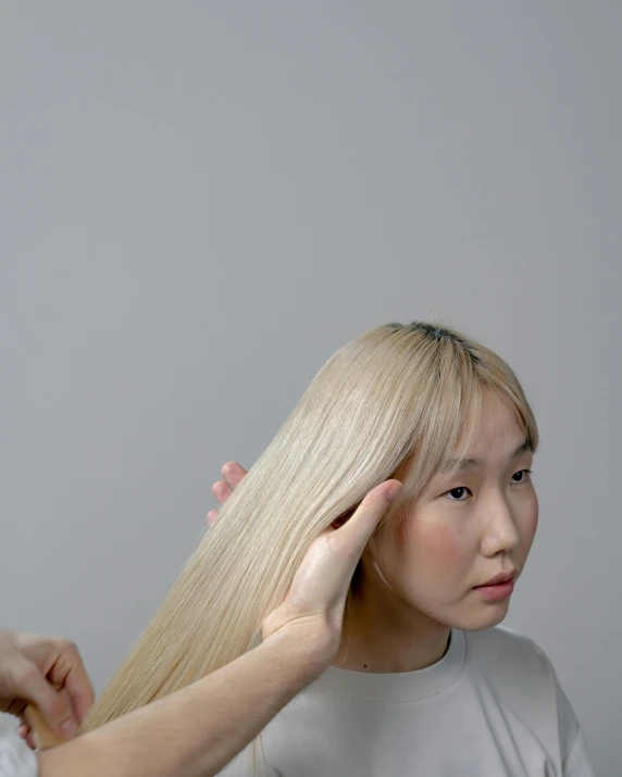 a woman is combing another woman's hair, by helen huang, extremely pale blond hair, jaeyeon nam, on a gray background, non binary model