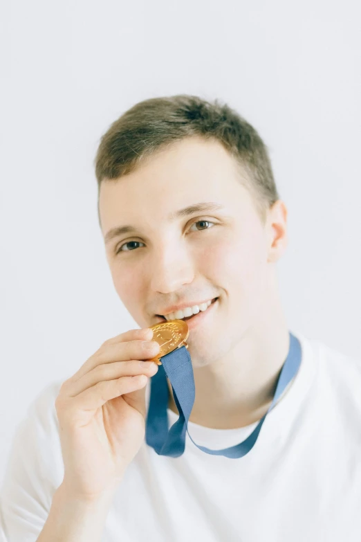 a boy eating a piece of food with a blue tie around his neck, an album cover, inspired by Ryan Pancoast, pexels contest winner, renaissance, medal, athlete photography, anna nikonova aka newmilky, headshot profile picture