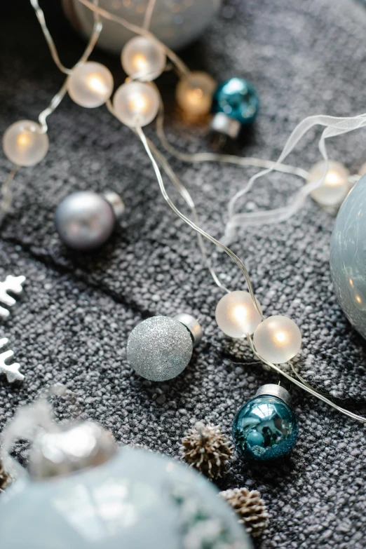 a close up of a christmas ornament on a table, a still life, trending on unsplash, light and space, pale cyan and grey fabric, lamps on ground, with sparking circuits, charcoal and silver color scheme