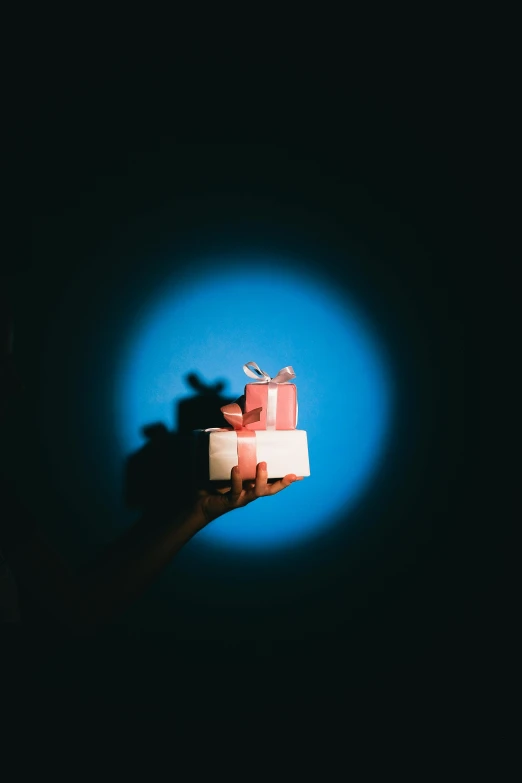 a person holding a bunch of presents in their hand, a hologram, by Adam Chmielowski, pexels, minimalism, square, 6 spotlight, blue and pink, shadow