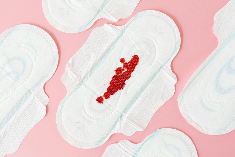 a group of sanitary pads sitting on top of a pink surface, by Julia Pishtar, blood splatter on the sides, silicone patch design, close-up product photo, red blood