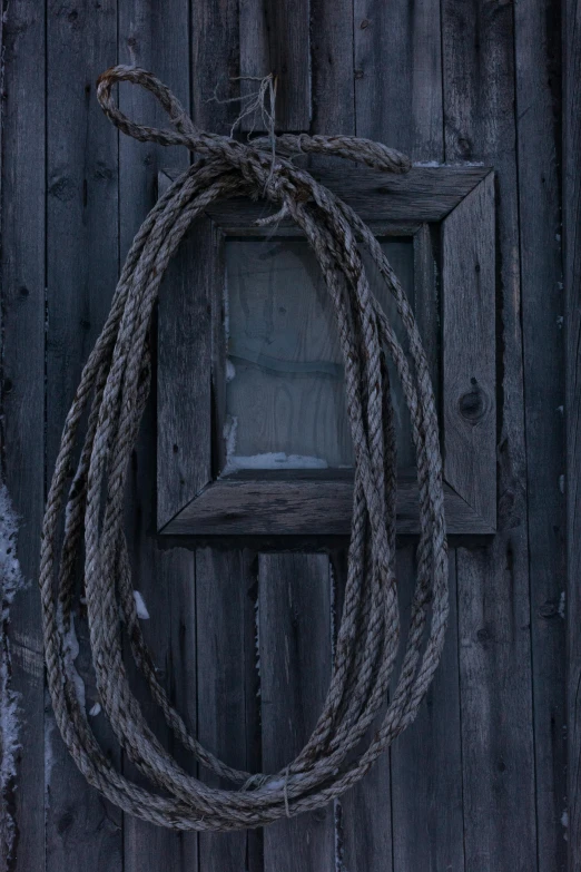 a rope hanging on the side of a wooden building, a picture, by Jan Tengnagel, pexels contest winner, dark grey, square, doorway, high quality photo