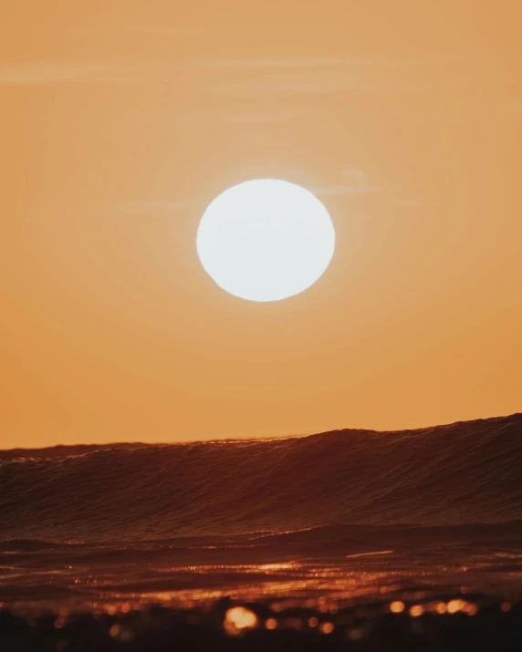 a person riding a surfboard on top of a wave, pexels contest winner, romanticism, suns set on a desert planet, big red sun, solar eclipse in iceland, nuclear sunset