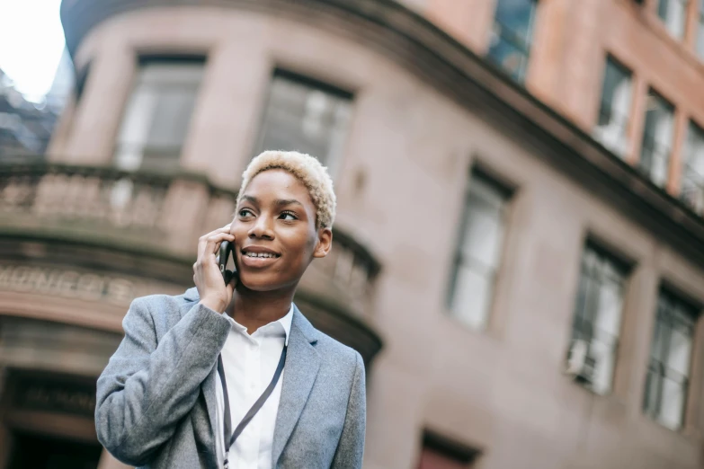 a woman talking on a cell phone in front of a building, black female, professional image, thumbnail, multiple stories