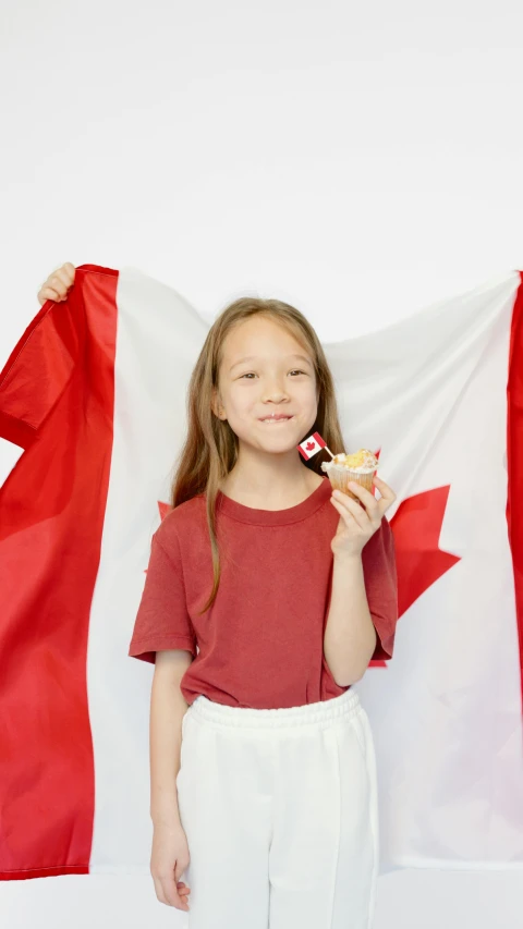 a little girl holding a canadian flag and eating a donut, an album cover, pexels, hi-res, feature, f