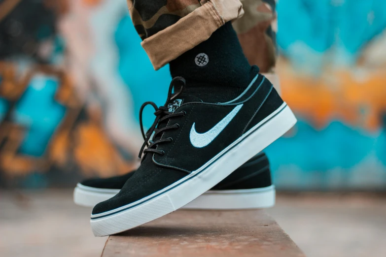 a person standing on a skateboard in front of a graffiti wall, pexels contest winner, nike logo, white font on black canvas, whole shoe is in picture, avatar image