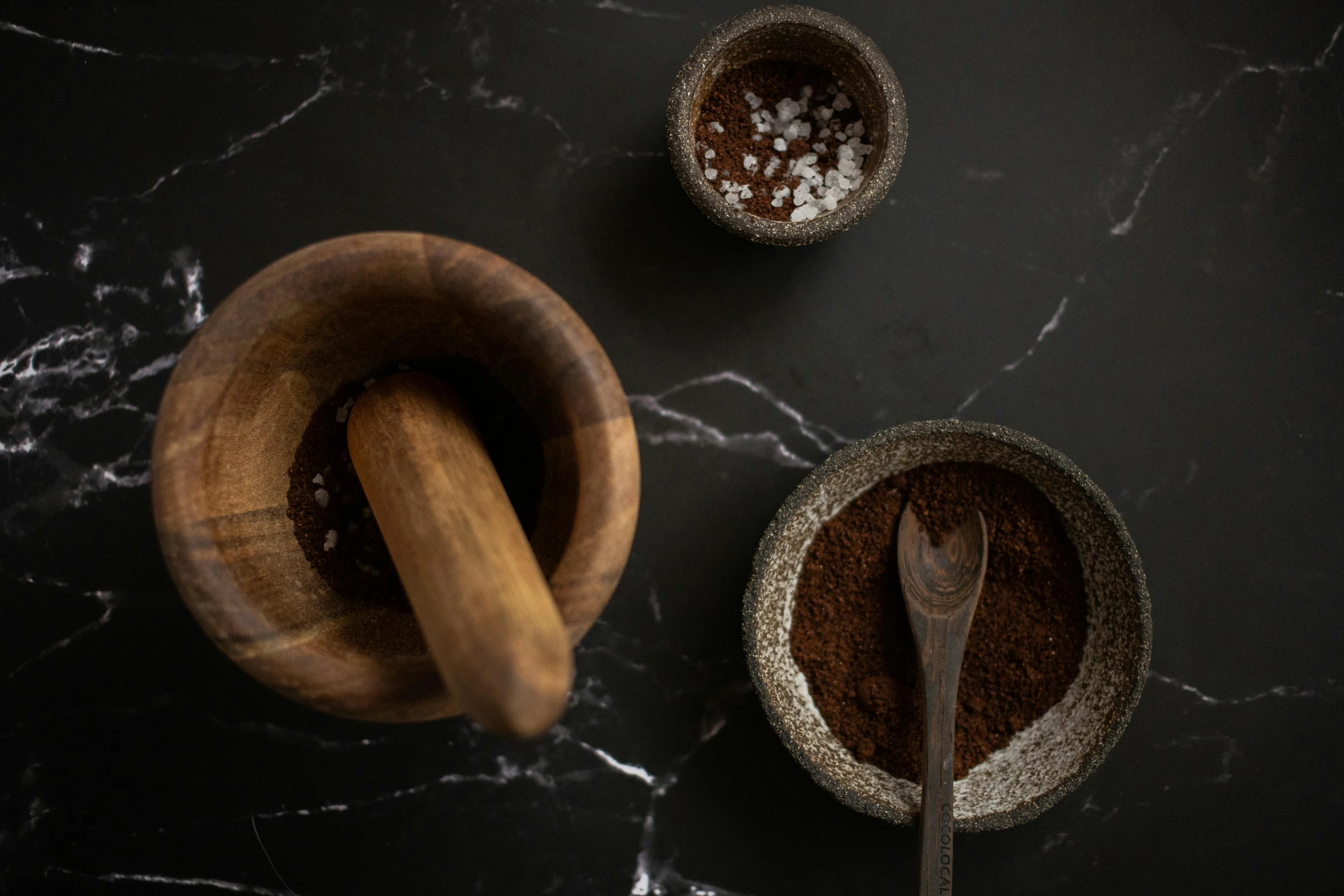 a table topped with bowls of food and a wooden spoon, a still life, inspired by Ceferí Olivé, trending on pexels, dark angel of coffee, powder, all marble, dark brown