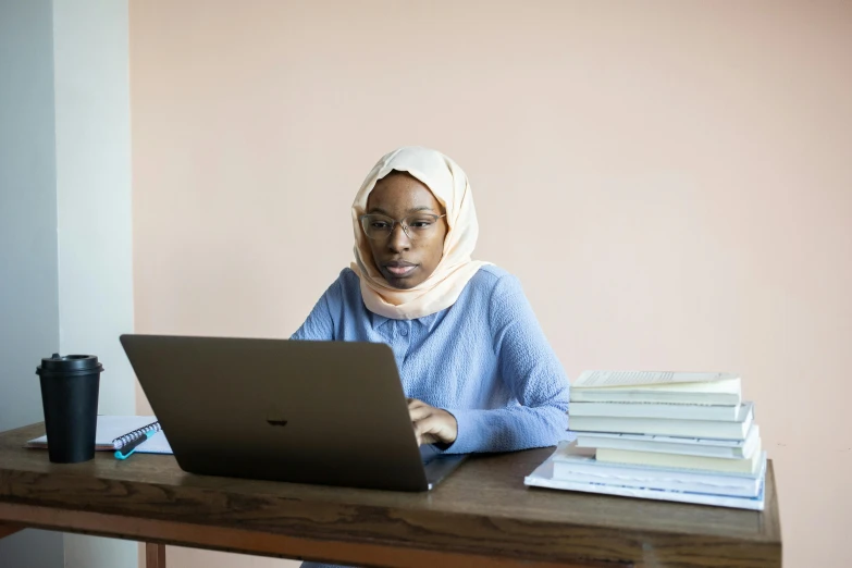 a woman sitting at a desk using a laptop computer, by Arabella Rankin, pexels contest winner, hurufiyya, riyahd cassiem, portrait of tall, teaching, stacked image