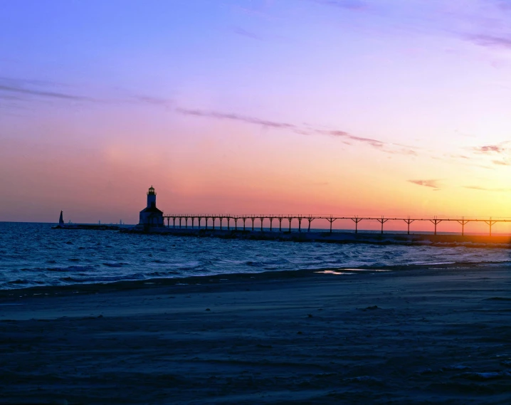 a lighthouse sitting on top of a sandy beach, during a sunset, bridges, midwest town, indigo