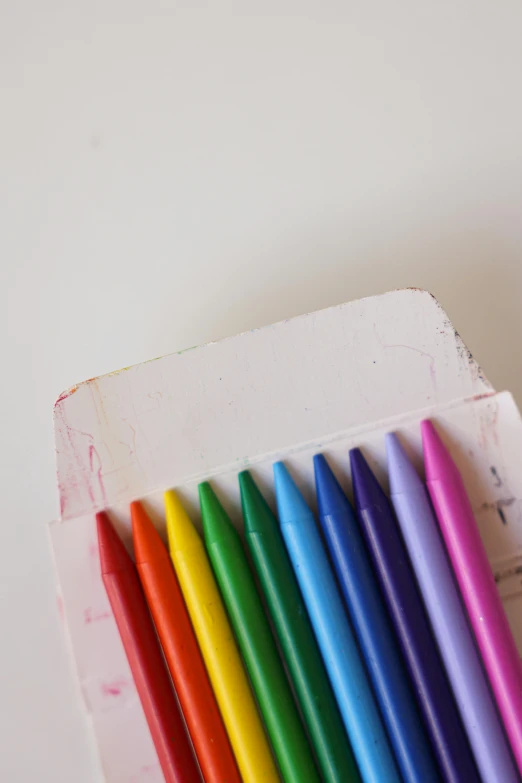 a box of colored crayons sitting on top of a table, an album cover, by Rachel Reckitt, unsplash, with a white background, bleached colours, opening shot, markers