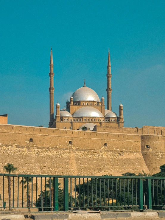 a man sitting on a bench in front of a building, dau-al-set, black domes and spires, 2022 photograph, egyptian, citadel