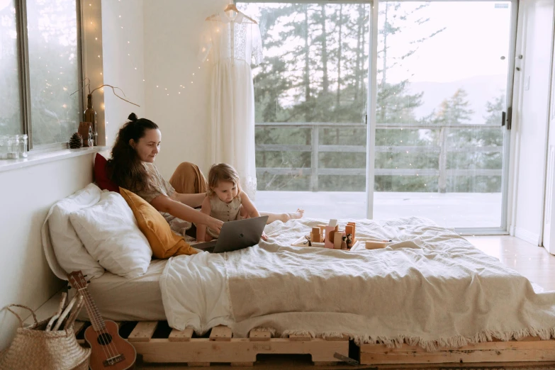 a woman sitting on top of a bed next to a child, pexels contest winner, afternoon hangout, everything fits on the screen, manuka, cardboard