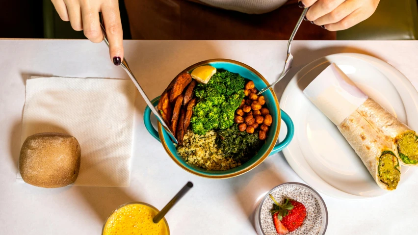 a person sitting at a table with a bowl of food, teal and orange colours, daily specials, ivy's, blending