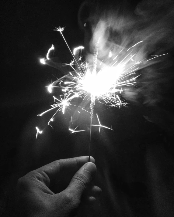 a person holding a sparkler in their hand, a black and white photo, instagram post, spangle, in 2 0 1 5, wikimedia