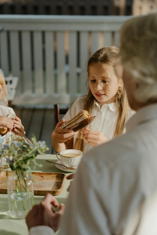 a group of people sitting around a table eating food, bread, cottagecore, kids, high resolution