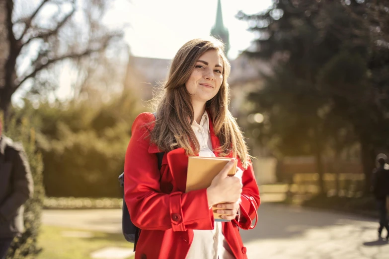 a woman in a red coat is holding a folder, by Julia Pishtar, shutterstock, academic art, sunny environment, portrait of high school girl, instagram picture, gold