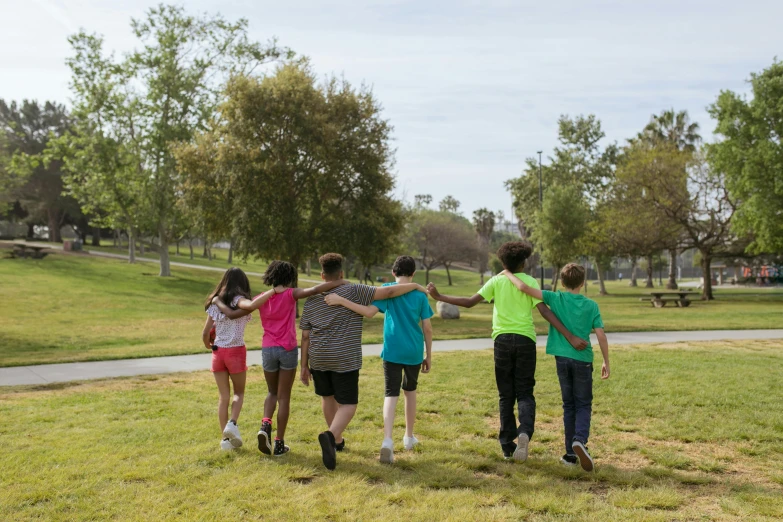 a group of people standing on top of a lush green field, at the park, profile image, kids, southern california