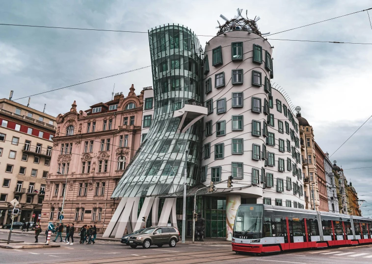 a bus driving down a street next to a tall building, a photo, pexels contest winner, art nouveau, frank gehry, prague, 🎀 🗡 🍓 🧚, square