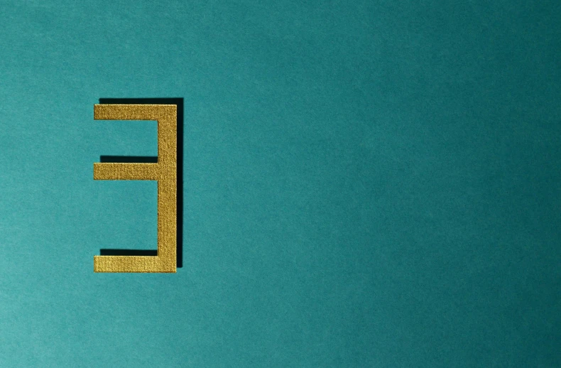 a close up of a letter e on a blue surface, an album cover, inspired by Josef Albers, pexels contest winner, hypermodernism, gold and teal color scheme, hebrew, fantasy - n 9, eight eight eight
