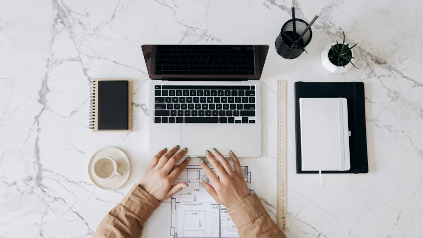 a person typing on a laptop on a marble desk, trending on unsplash, architectural plans, 9 9 designs, sustainable materials, flatlay