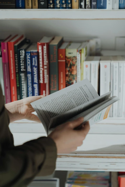 a person reading a book in front of a bookshelf, pexels contest winner, casually dressed, book title visible, video, without text