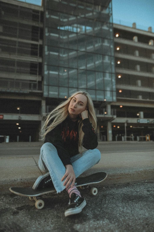 a woman sitting on a skateboard in front of a building, wearing jeans and a black hoodie, portrait featured on unsplash, amy sol in the style of, perched on a skyscraper