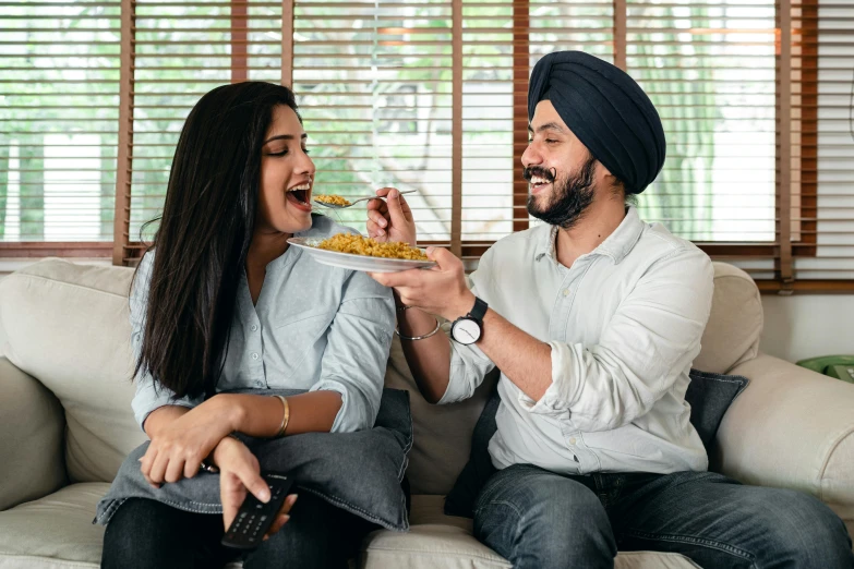 a man and a woman sitting on a couch eating food, inspired by Manjit Bawa, pexels contest winner, head bent back in laughter, profile image, mid shot, fan favorite