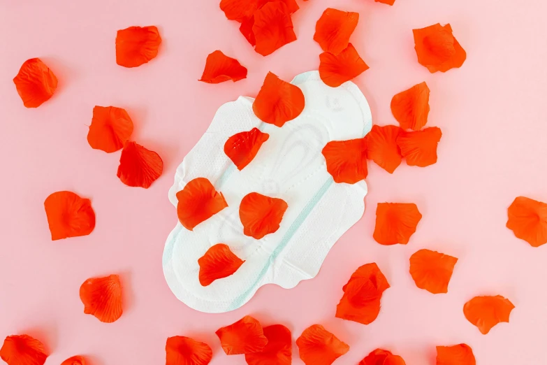 a baby diaper surrounded by rose petals on a pink background, by Julia Pishtar, happening, bright red, contracept, soft pads, cosmopolitan
