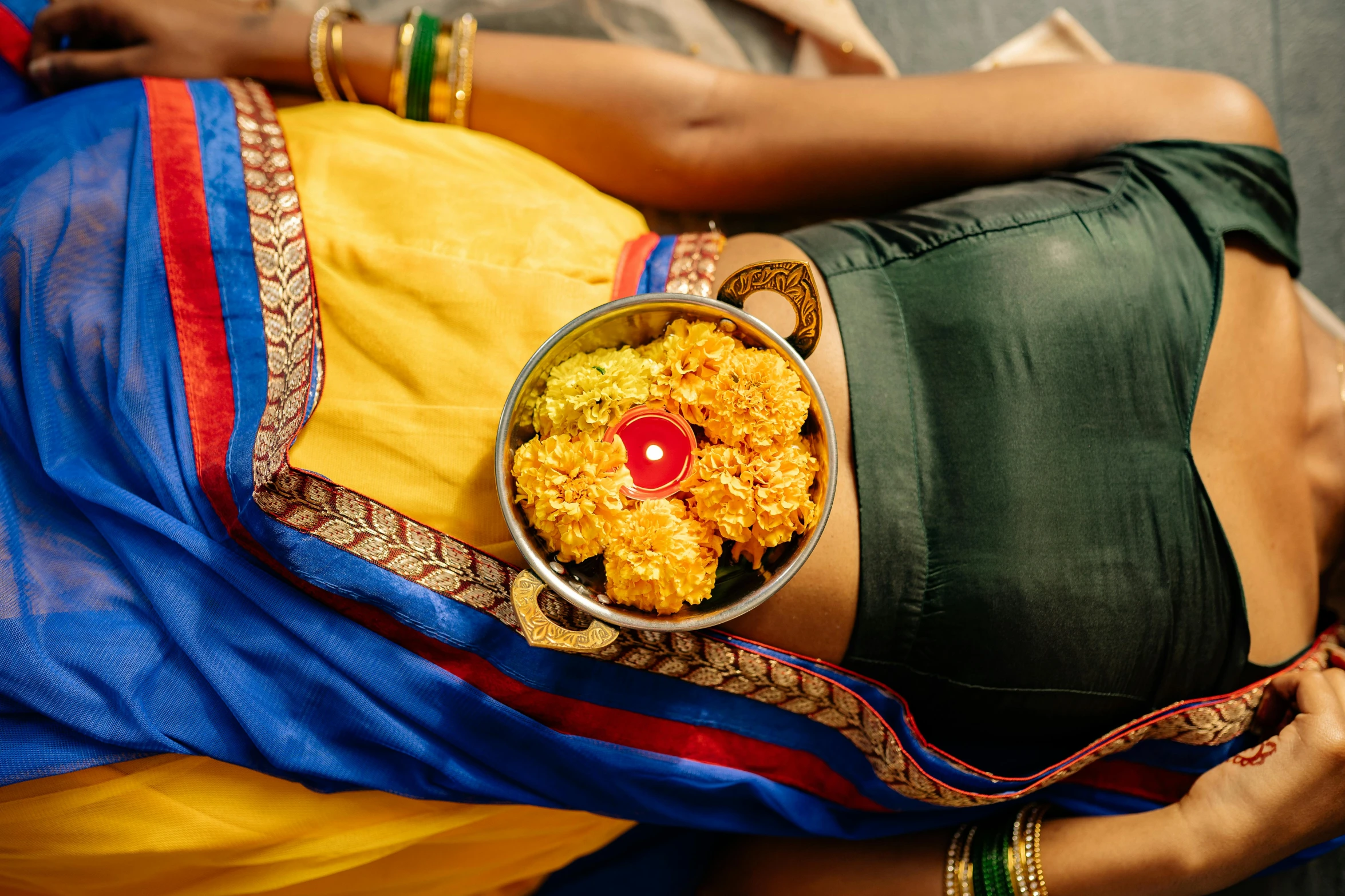 a woman laying down with a bowl of food, samikshavad, colorful adornments, third trimester, with yellow cloths, promo image