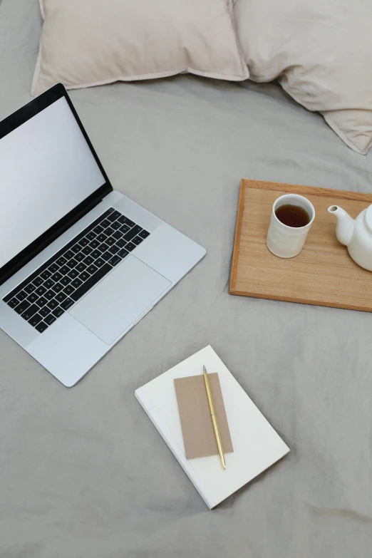 a laptop computer sitting on top of a bed next to a cup of coffee, 9 9 designs, curated collections, white, vanilla