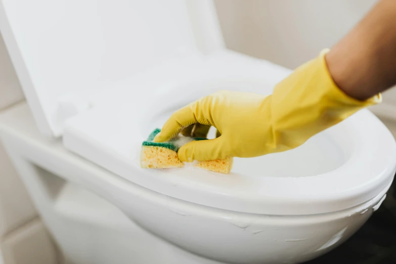 a person cleaning a toilet with a sponge, by Julia Pishtar, pexels contest winner, yellow latex gloves, avatar image, dezeen, gaming chair as a toilet